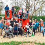 Helfergruppe mit neuem Spielgerät auf dem Spielplatz