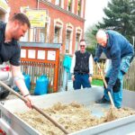 Helfer schaufeln Sand aus einer Schubkarre