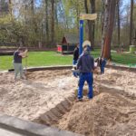 Helfer bei der Erneuerung einer Sandfläche auf einem Spielplatz